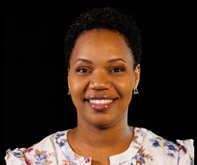 A woman named Kiara Matthews with short hair wearing a floral shirt, smiling at the camera.