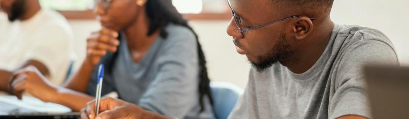 A diverse group of students seated at desks in a classroom, engaged in discussion and learning activities.