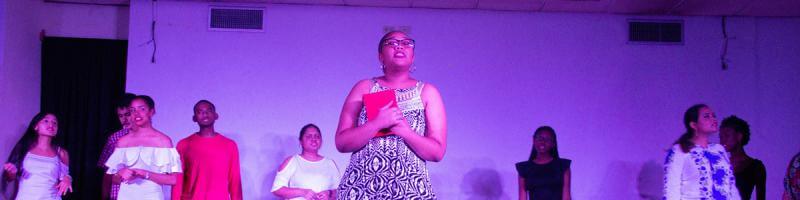 A woman and others are on stage, representing the BA French program at an academic event, engaging the audience.