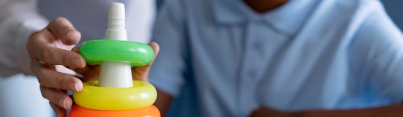 A young child grips a vibrant toy set, illustrating playful engagement in role-playing activities.