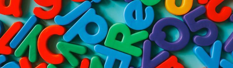 Colourful plastic letters arranged in a vibrant pattern, showcasing various shapes and colours.