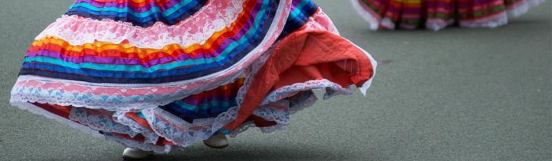 A woman in a vibrant, colourful dress strolls down a lively street, showcasing her style and confidence.