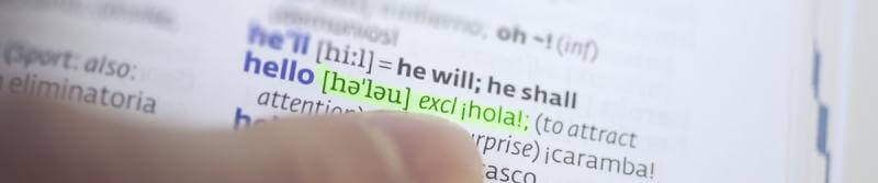 A close-up of a person's hand gripping a dictionary, showcasing the word hello.