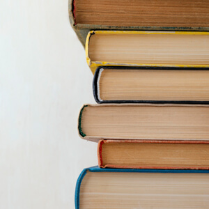 A stack of colourful books arranged neatly on a white background, showcasing various titles and sizes.