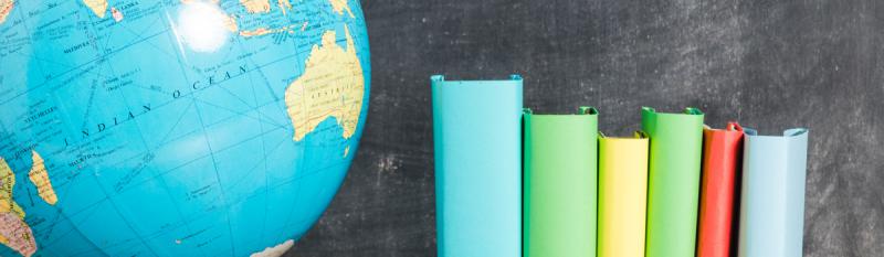 A globe surrounded by colourful books, with a chalkboard in the background displaying educational content.