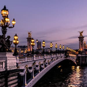 The Seine River bridge in Paris at dusk, illuminated by soft lights against a twilight sky.