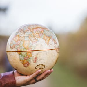 A person holds a globe in their hand.