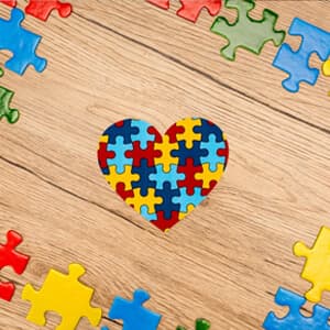 A heart-shaped puzzle piece rests on a wooden table, symbolising love and connection.