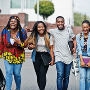 Four young individuals walking side by side on a city street, engaged in conversation and enjoying their time together.