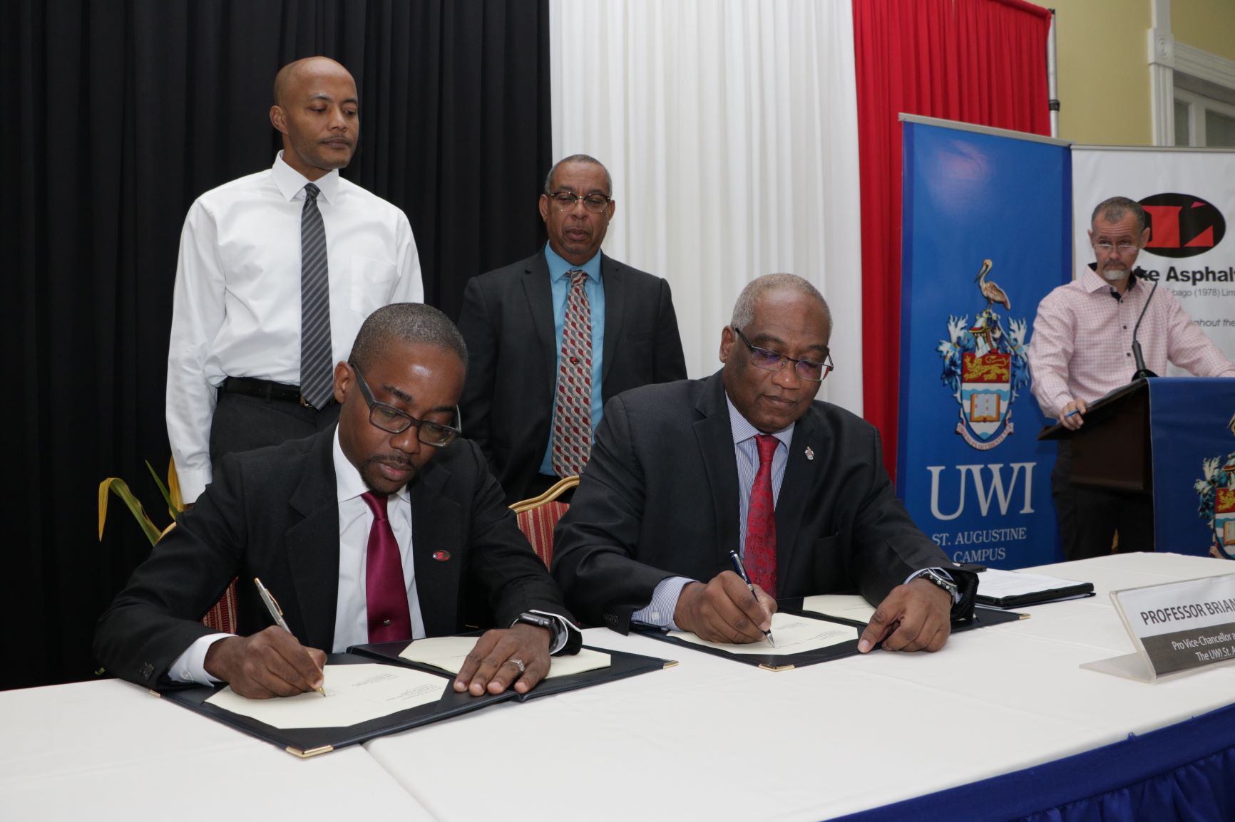  Chief Executive Officer of Lake Asphalt of Trinidad and Tobago Ltd., Mr Roger Wiggins and Pro Vice-Chancellor and Campus Principal of The UWI St Augustine, Professor Brian Copeland sign the licence agreement. Looking on are Dr. Richard Fairman, Head, Department of Chemistry, Mr. Stephen Mc Clashie, Director, Lake Asphalt and Mr. Julian Henry Programme Manager, The Entrepreneurship Unit.